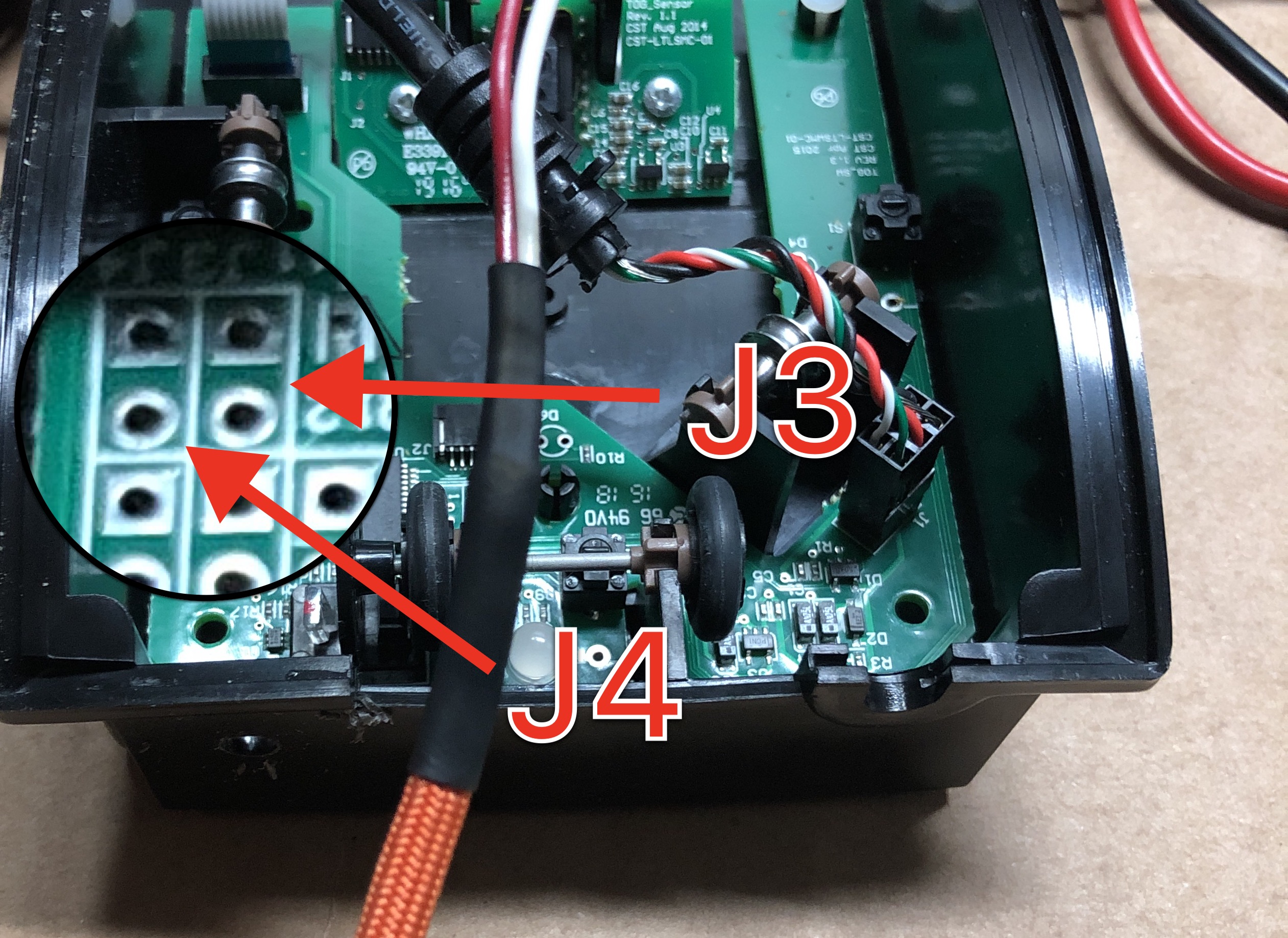 Solder pads indicated in magnification with red arrows